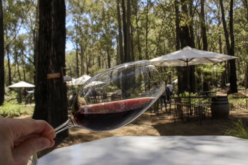 A single wine glass held by the stem and tilted over a white tabletop to show the wine's color, soft daylight, no text, no logos, no people